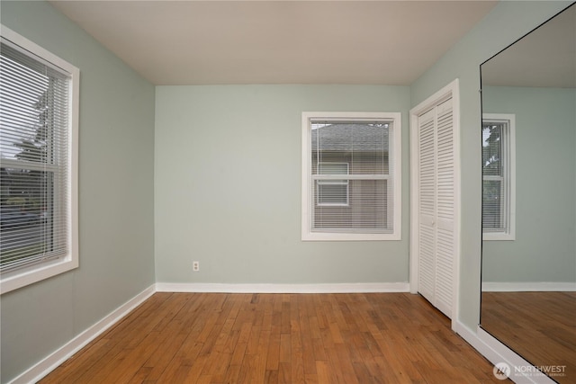 unfurnished bedroom featuring a closet, baseboards, and wood-type flooring