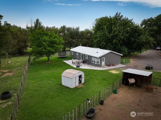 back of house with an outbuilding, a trampoline, fence, a yard, and an outdoor structure