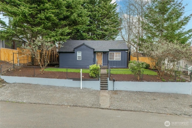 view of front facade featuring a fenced front yard and a shingled roof