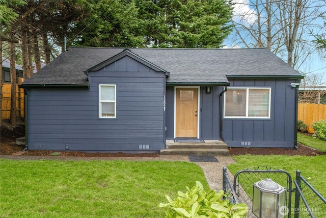 view of front facade with a front lawn, fence, board and batten siding, and a shingled roof