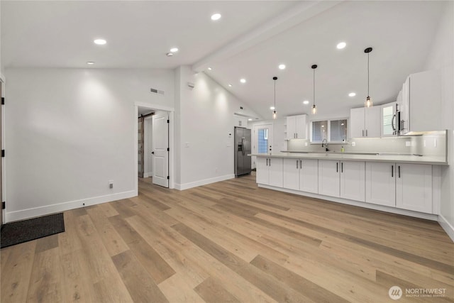 kitchen with stainless steel refrigerator with ice dispenser, a barn door, light wood-style floors, a peninsula, and white cabinets