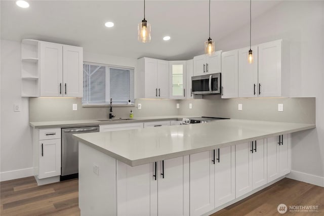 kitchen with white cabinetry, a peninsula, appliances with stainless steel finishes, and a sink