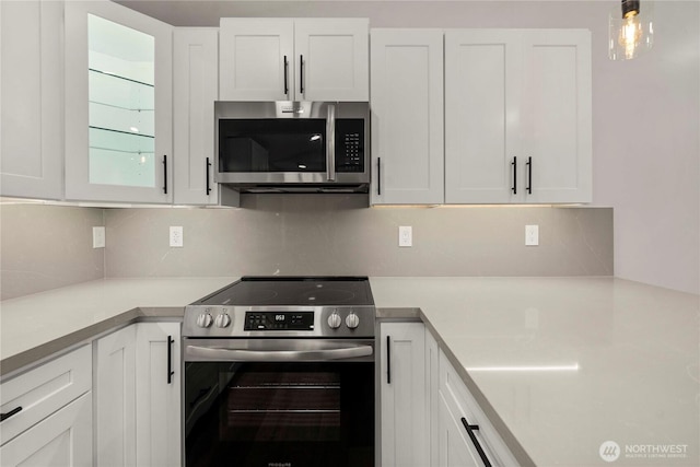 kitchen featuring decorative backsplash, light countertops, white cabinets, and stainless steel appliances