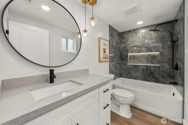 full bath featuring vanity, wood finished floors, visible vents, shower / washtub combination, and toilet