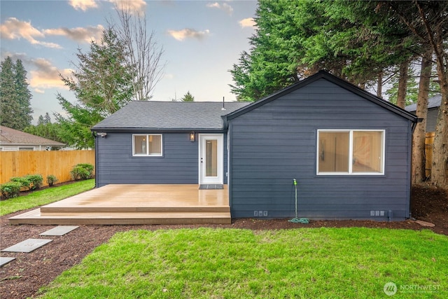 rear view of property with a deck, fence, a yard, roof with shingles, and crawl space