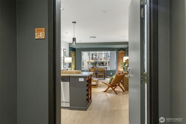 kitchen with stainless steel dishwasher, recessed lighting, light wood-style floors, light countertops, and hanging light fixtures