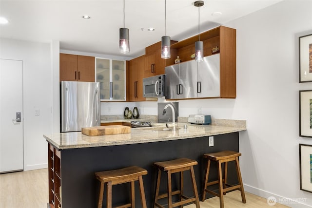 kitchen featuring open shelves, appliances with stainless steel finishes, a peninsula, and brown cabinetry