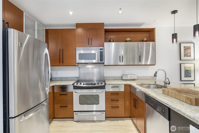 kitchen with light stone countertops, brown cabinets, appliances with stainless steel finishes, and a sink