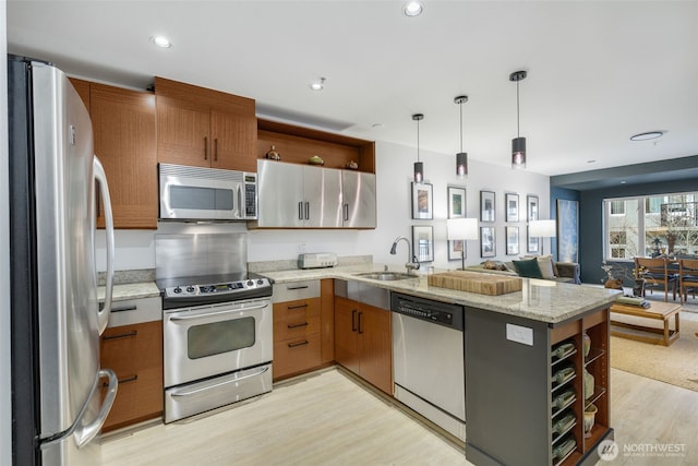 kitchen featuring a sink, open floor plan, appliances with stainless steel finishes, a peninsula, and open shelves