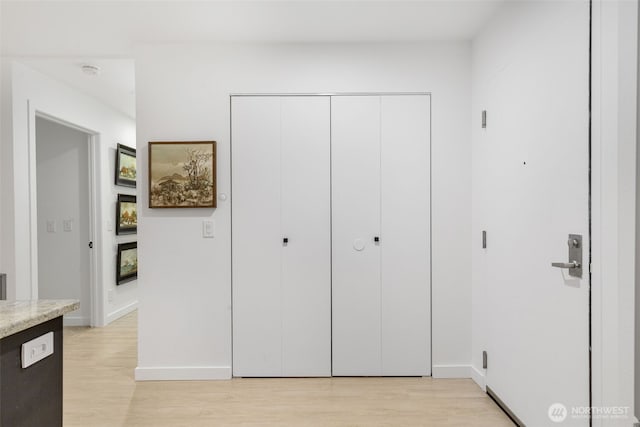 bedroom with a closet, baseboards, and light wood-style floors