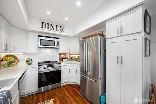 kitchen with dark wood-type flooring, backsplash, white cabinetry, stainless steel appliances, and light countertops