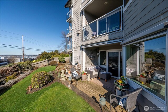 exterior space featuring a balcony, a patio area, fence, and an outdoor hangout area