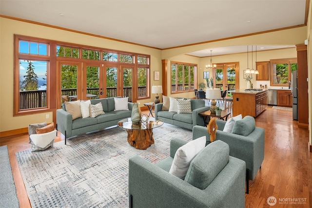 living area with french doors, baseboards, light wood finished floors, and a chandelier