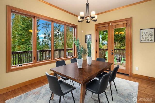 dining room featuring a chandelier, baseboards, light wood-style flooring, and crown molding