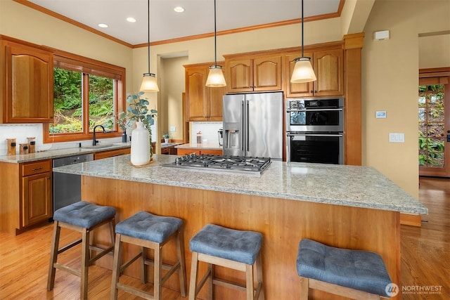 kitchen featuring a sink, light stone countertops, light wood-style floors, and appliances with stainless steel finishes