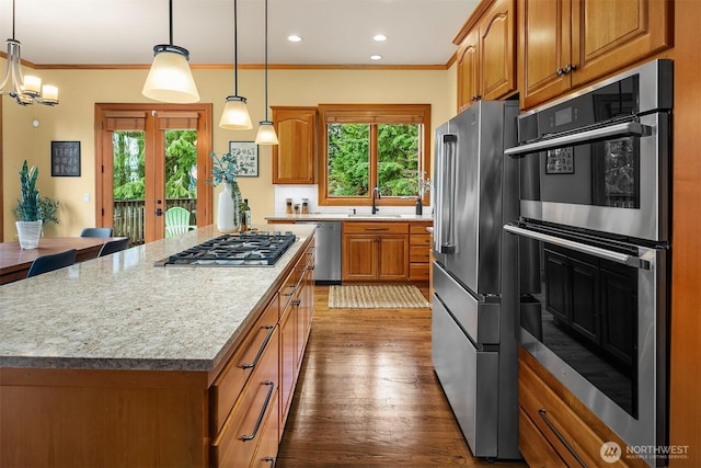 kitchen featuring a healthy amount of sunlight, stainless steel appliances, ornamental molding, and a sink