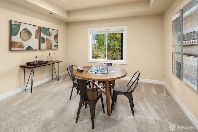 dining space featuring a tray ceiling, carpet flooring, visible vents, and baseboards