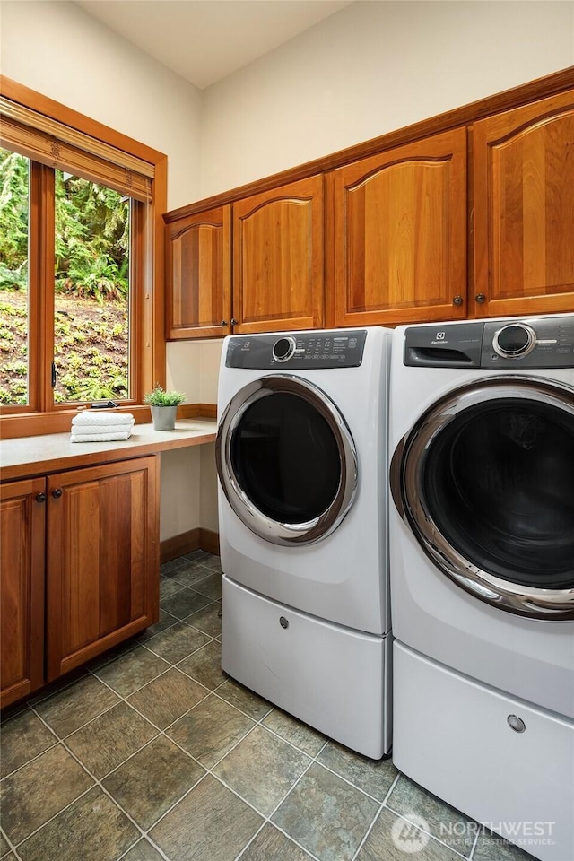 clothes washing area with washer and clothes dryer and cabinet space