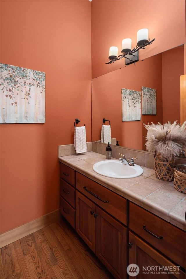 bathroom featuring vanity, baseboards, and wood finished floors