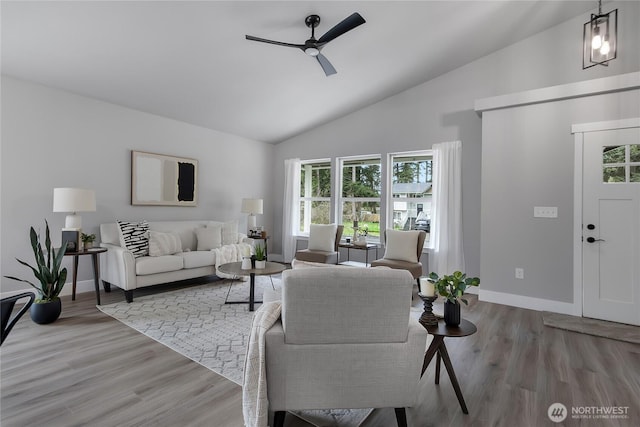 living area with baseboards, light wood-style floors, ceiling fan, and vaulted ceiling