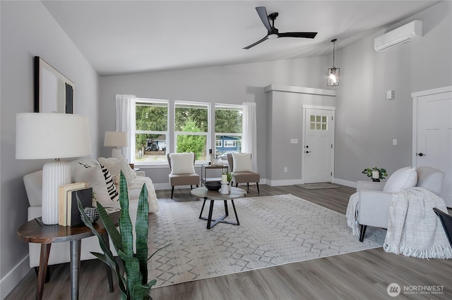 living area featuring a ceiling fan, wood finished floors, baseboards, lofted ceiling, and a wall mounted air conditioner