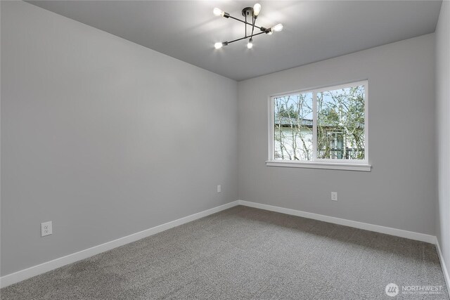 unfurnished room featuring a notable chandelier, baseboards, and carpet floors