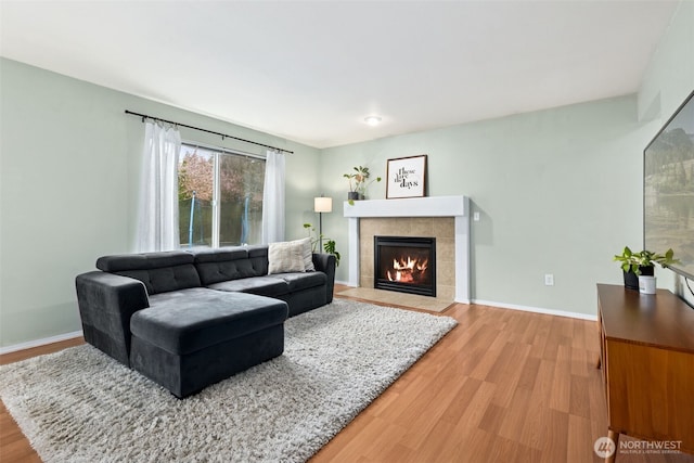 living area featuring a fireplace, wood finished floors, and baseboards