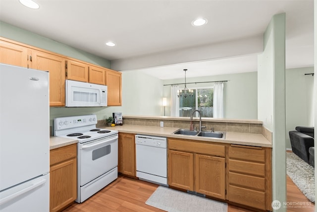 kitchen with light wood-type flooring, light countertops, recessed lighting, white appliances, and a sink