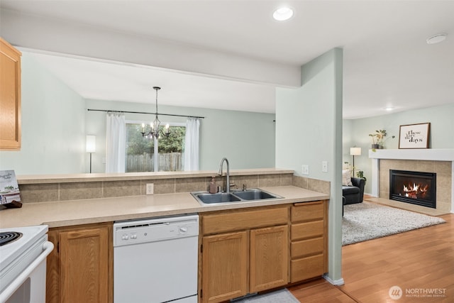 kitchen with light wood-style flooring, a sink, white appliances, a fireplace, and light countertops