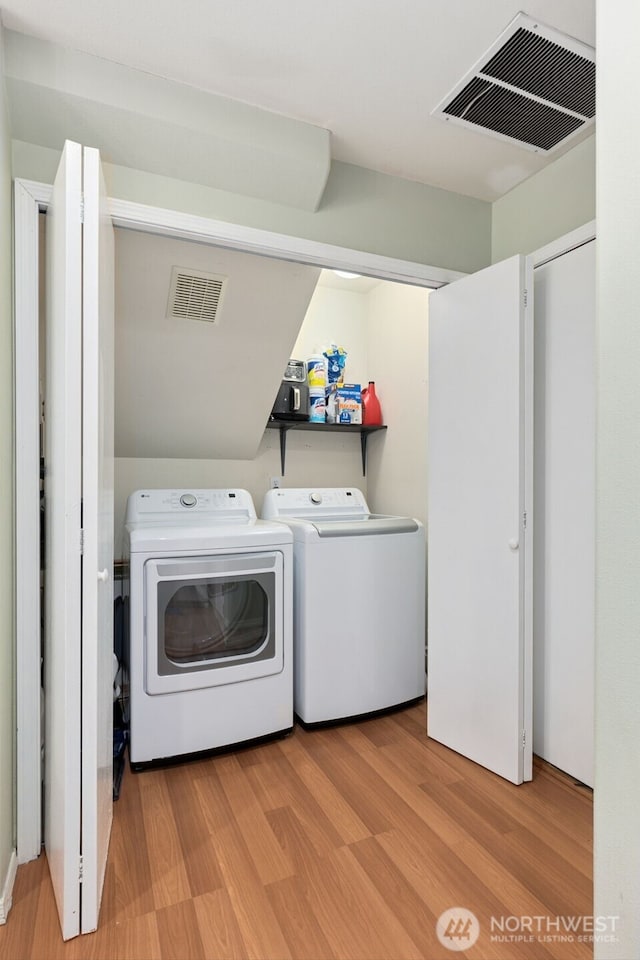 laundry room featuring visible vents, separate washer and dryer, wood finished floors, and laundry area