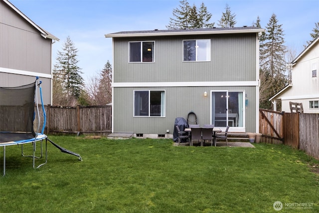 back of property featuring a fenced backyard, a lawn, and a trampoline