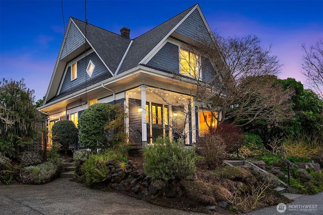 shingle-style home with a chimney and roof with shingles