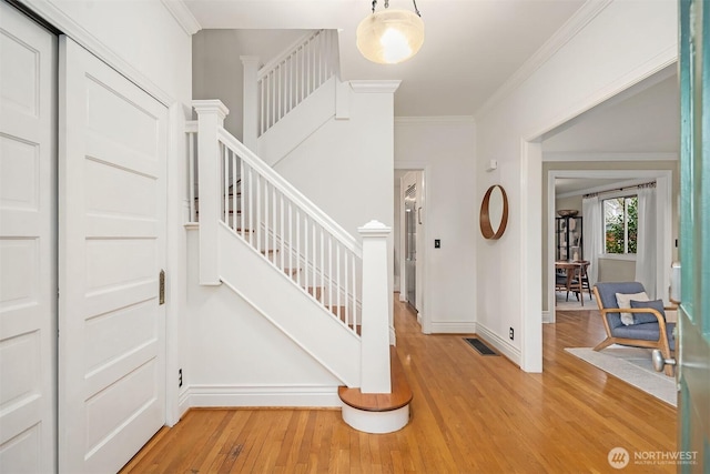 stairway featuring visible vents, wood finished floors, baseboards, and ornamental molding