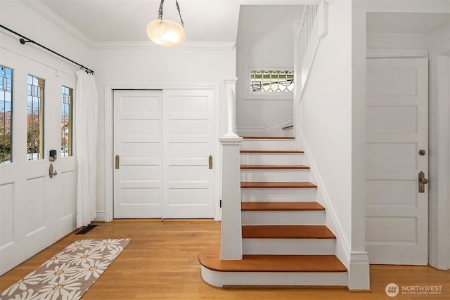 foyer with stairway, wood finished floors, visible vents, and ornamental molding