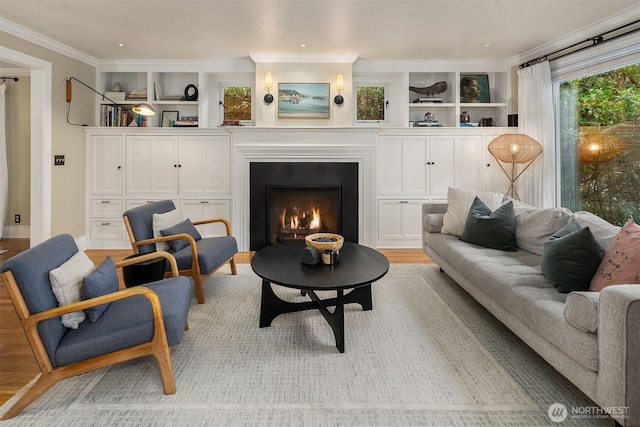 living area with light wood-style floors, built in shelves, a lit fireplace, and ornamental molding