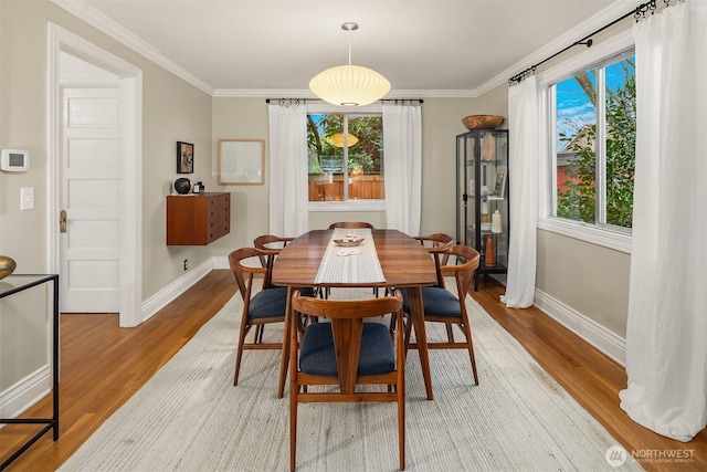 dining room with light wood-type flooring, baseboards, and ornamental molding