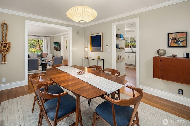 dining space featuring baseboards, wood finished floors, and ornamental molding