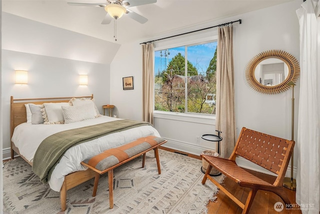 bedroom with vaulted ceiling, light wood-style flooring, baseboards, and ceiling fan