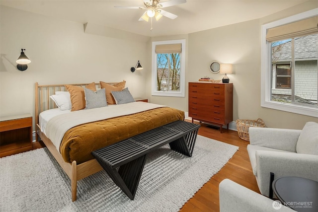 bedroom featuring ceiling fan, multiple windows, and wood finished floors