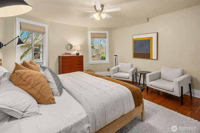 bedroom with ceiling fan, baseboards, multiple windows, and wood finished floors