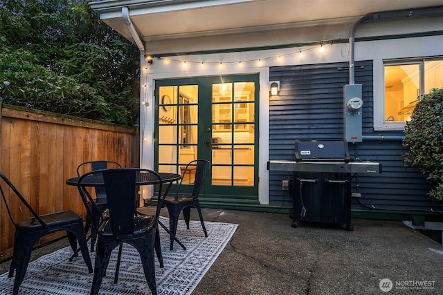 view of patio with outdoor dining space, french doors, fence, and grilling area