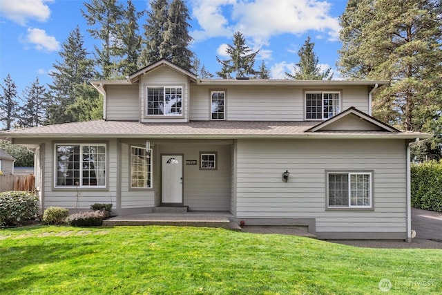 traditional-style home featuring roof with shingles and a front lawn