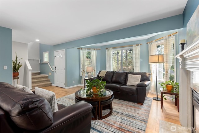 living area with stairway, light wood-style flooring, and baseboards