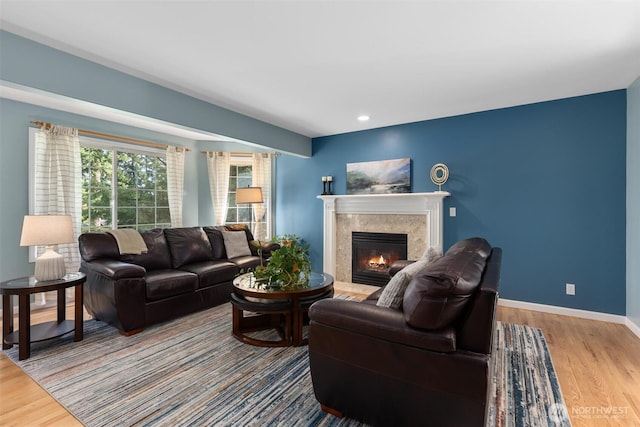 living area with recessed lighting, wood finished floors, baseboards, and a premium fireplace