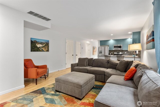 living room featuring recessed lighting, visible vents, baseboards, and light wood finished floors