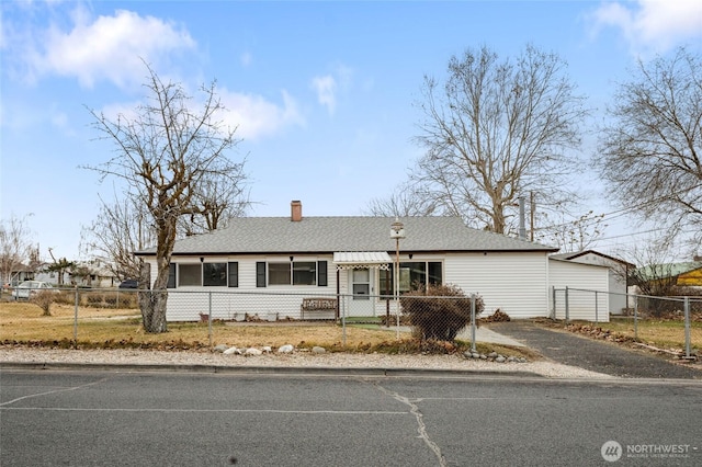 ranch-style house featuring a fenced front yard, aphalt driveway, and roof with shingles