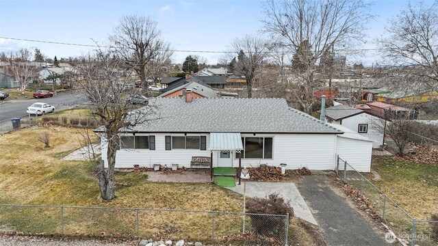 view of front of property featuring a fenced front yard, a front lawn, and roof with shingles