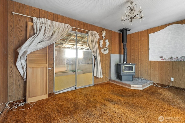 interior space with wooden walls, carpet, and a wood stove