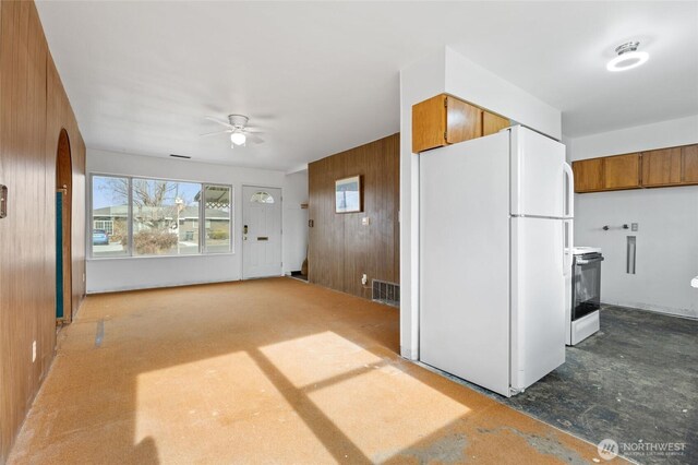 kitchen with white appliances, wooden walls, brown cabinetry, visible vents, and arched walkways