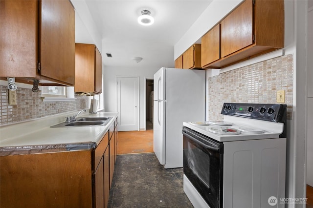 kitchen with range with electric cooktop, backsplash, freestanding refrigerator, brown cabinetry, and a sink